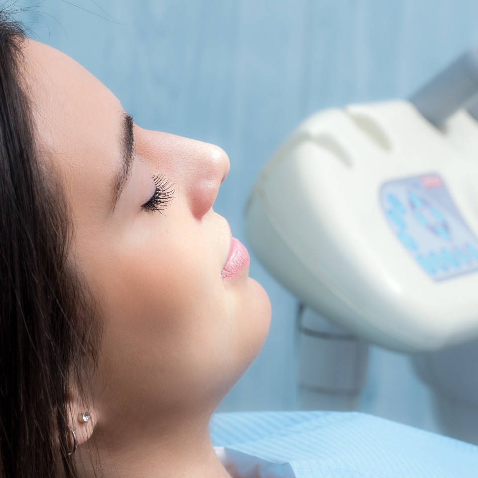 Side view of a young woman relaxing with eyes closed during a dental checkup