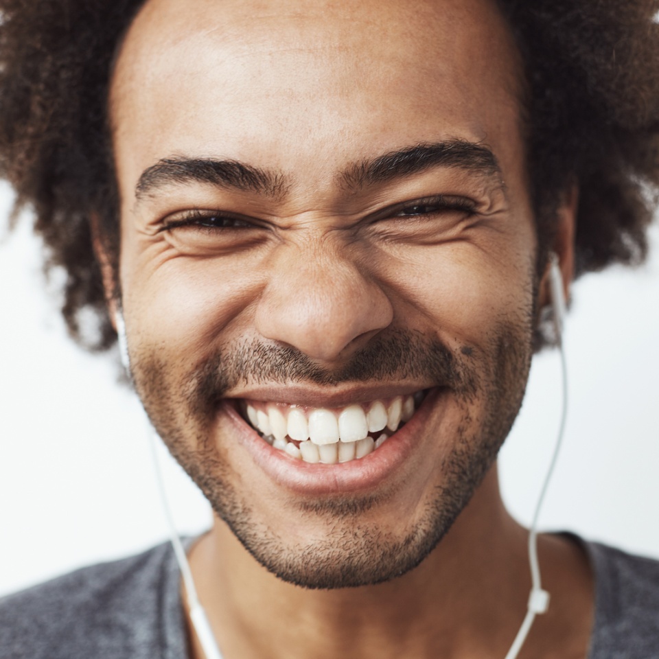 Smiling young man laughing while listening to music with headphones