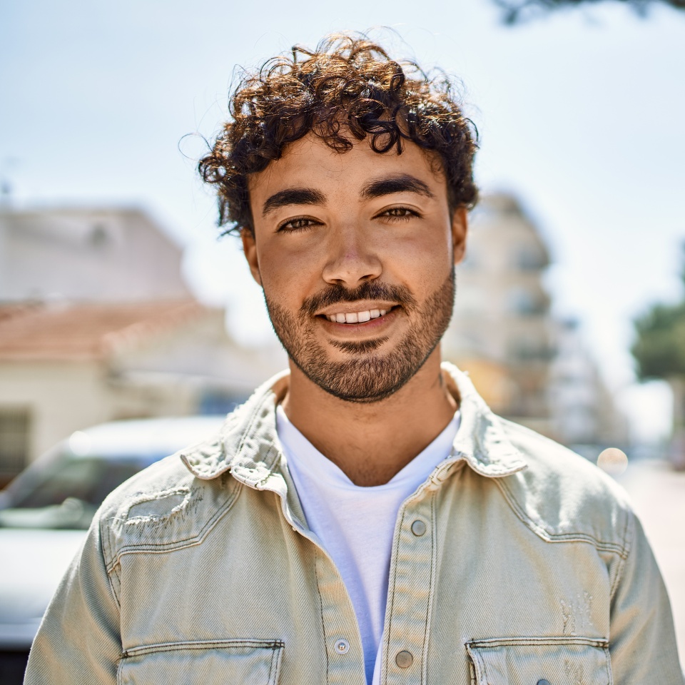 Smiling bearded man standing outdoors on a sunny day