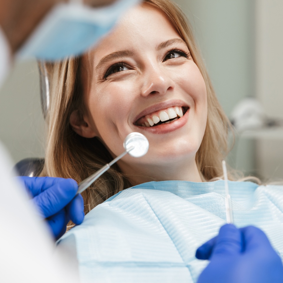 Young woman sitting in a dental chair while a dentist examines her teeth