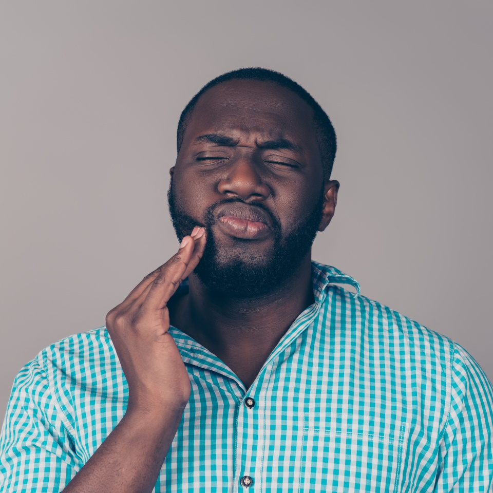 Bearded man touching his cheek in discomfort from a toothache