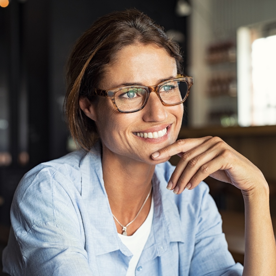 Mature woman in eyeglasses smiling while sitting at a cafe