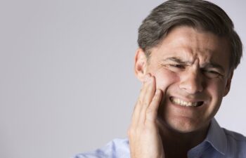 Studio portrait of a man holding his jaw in pain from a toothache