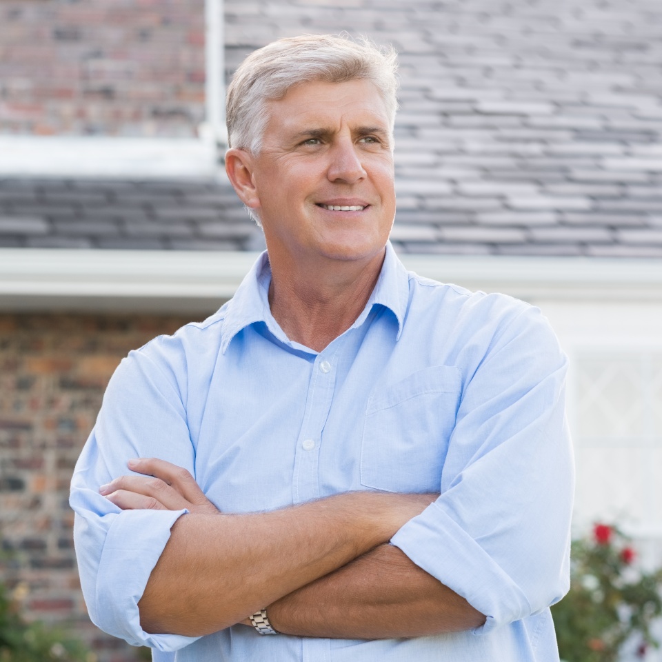 Smiling senior man standing with arms crossed, looking confident