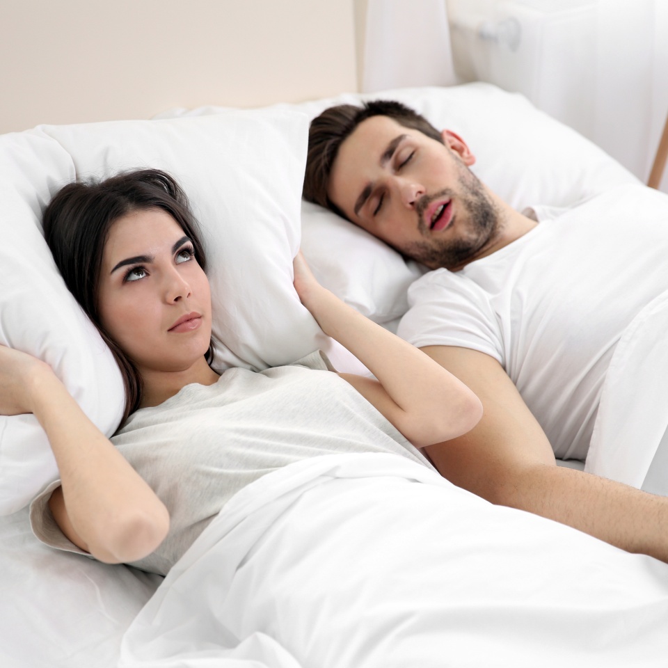 Woman unable to sleep next to a man snoring in bed