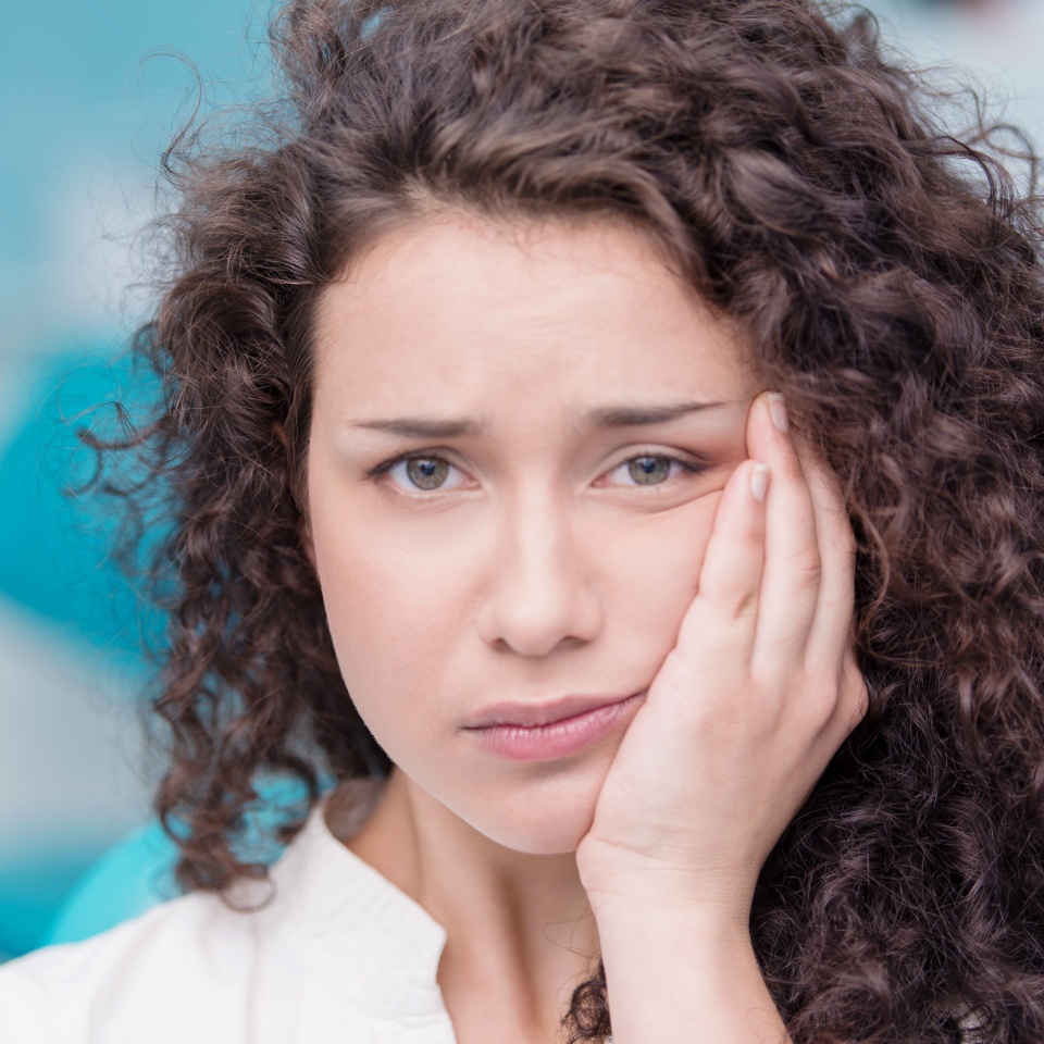 Young woman holding her cheek in pain from a toothache