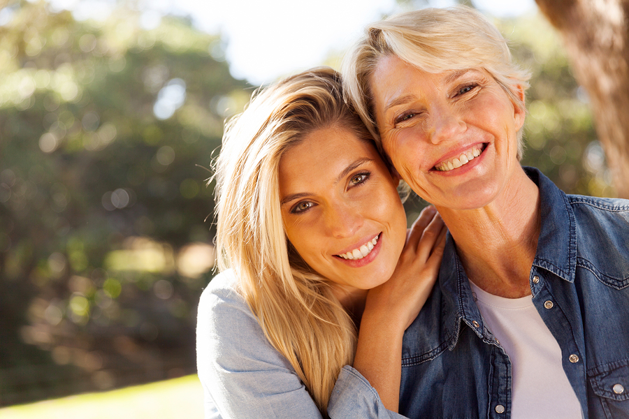Happy mother and adult daughter smiling together outdoors
