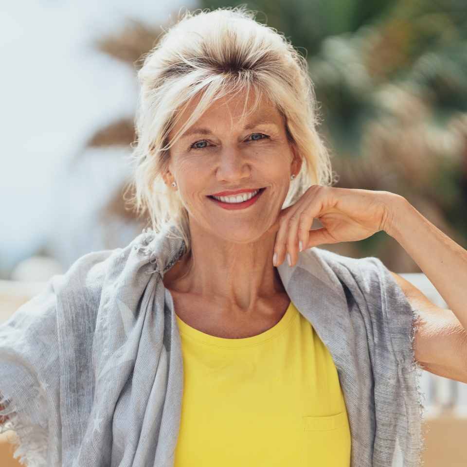 Smiling blonde woman sitting outdoors with a shawl over her shoulders