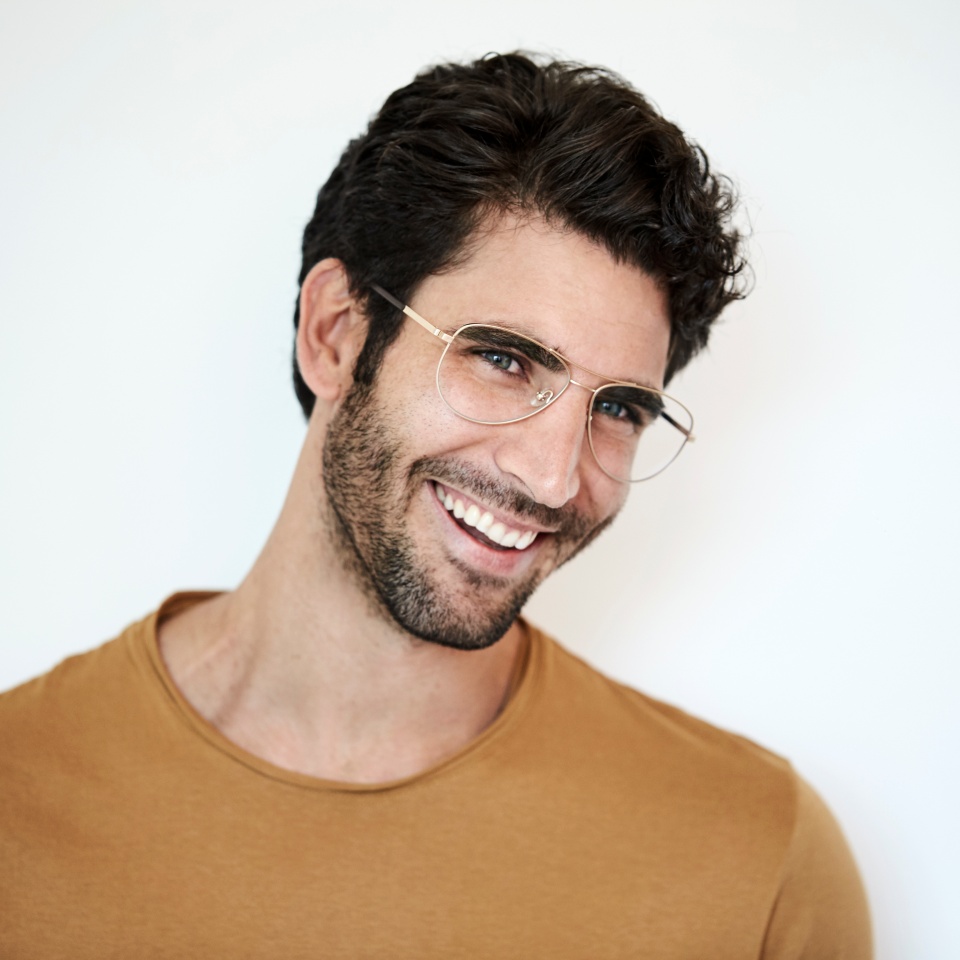 Man in glasses smiling against a white background