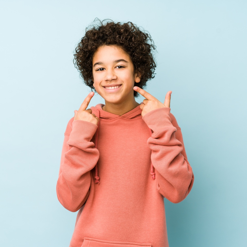 Smiling little boy pointing at his mouth
