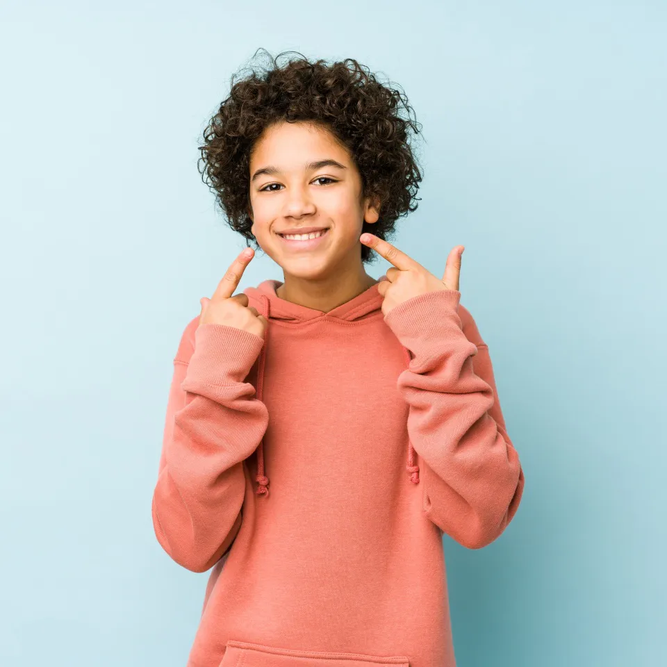 Smiling little boy pointing at his mouth