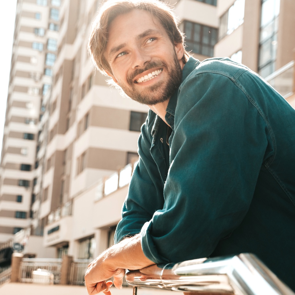 Smiling man in a green shirt standing on a city street