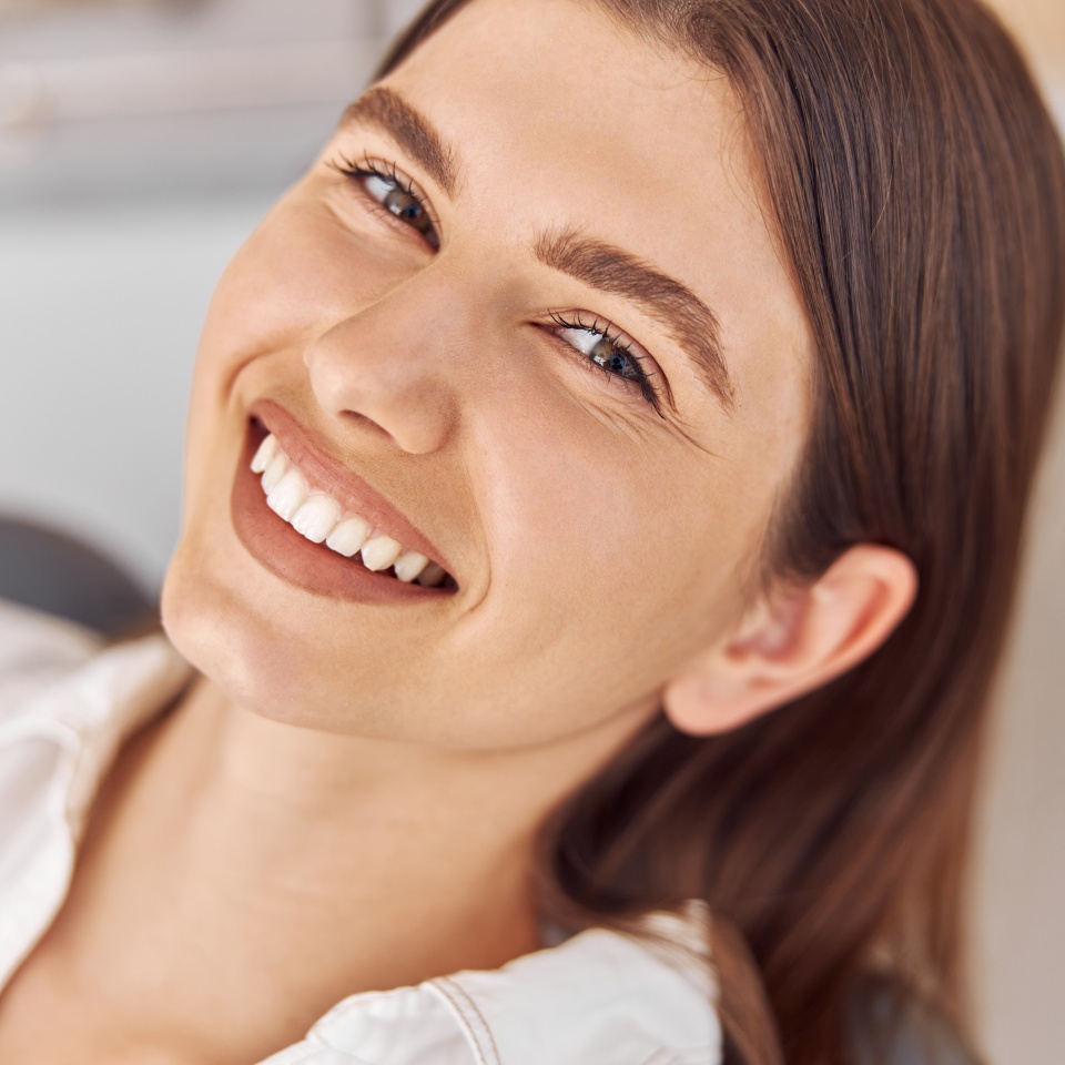 Happy young woman sitting in a dental chair at the office
