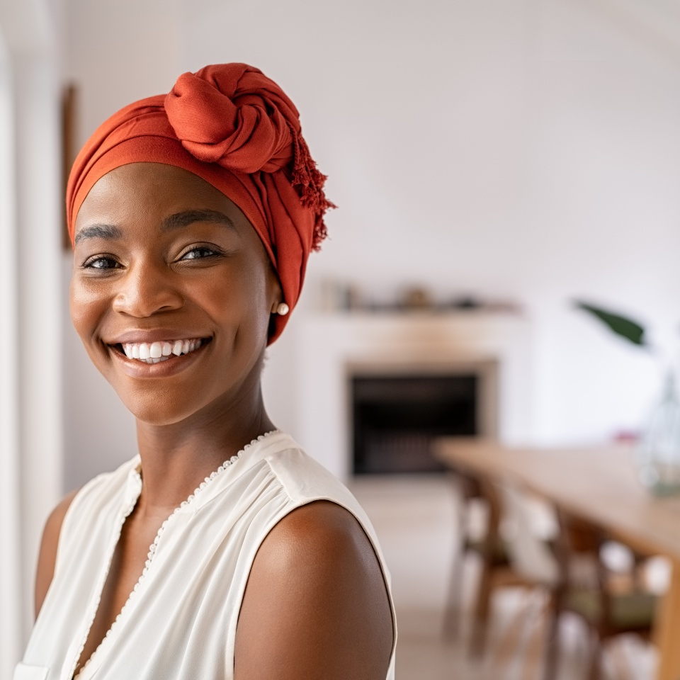 Smiling woman in a headscarf standing near a window