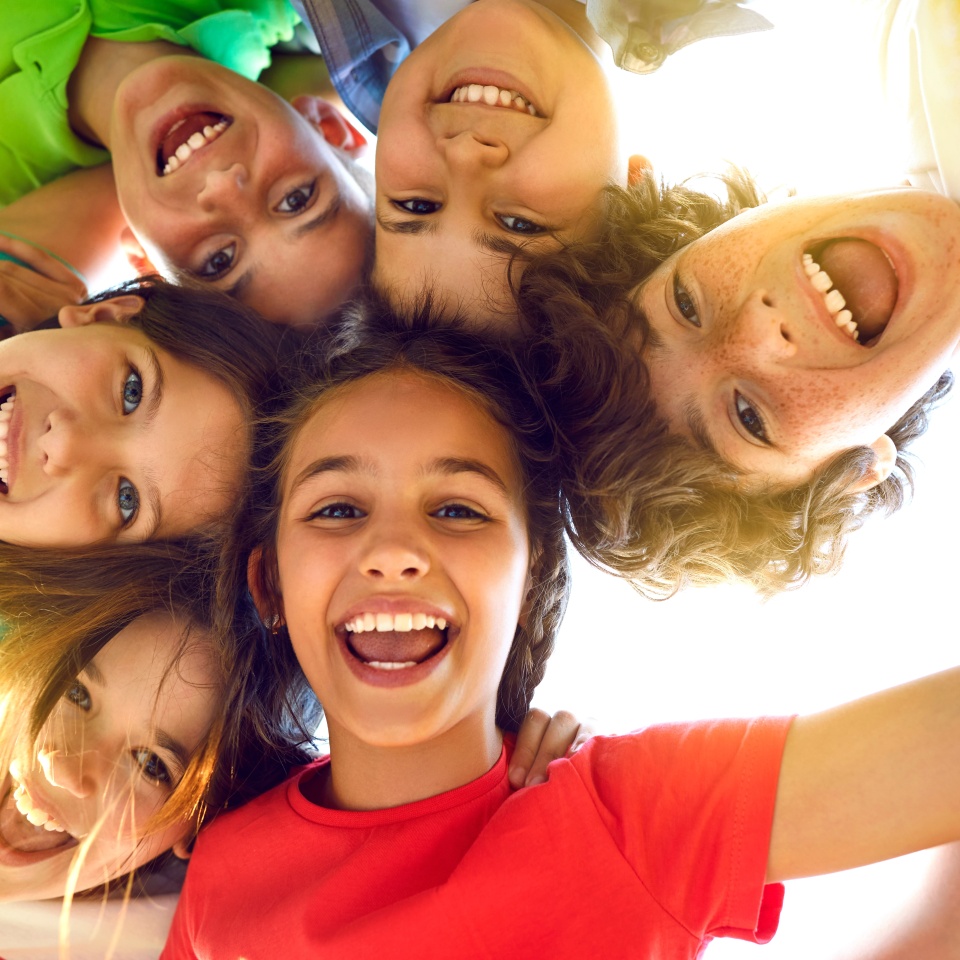Group of cheerful children huddled together smiling down at the camera