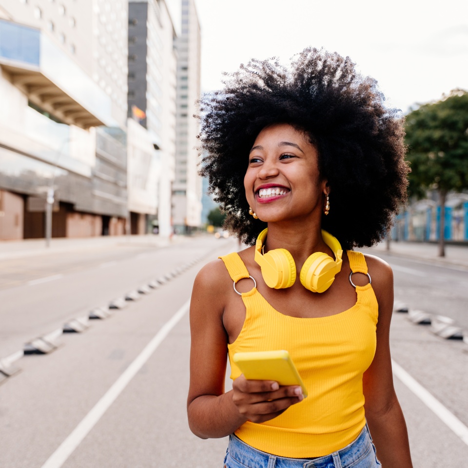 Cheerful young woman with curly afro hair walking in the city
