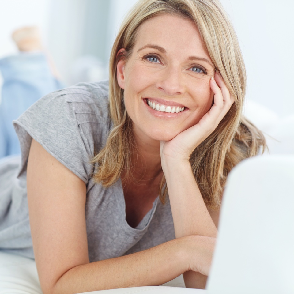 Mature woman relaxing and smiling on a sofa at home