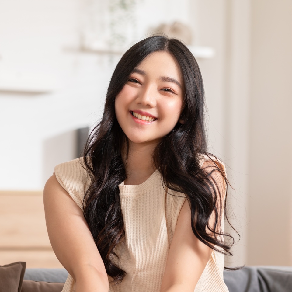 Young woman smiling confidently while relaxing on a couch at home