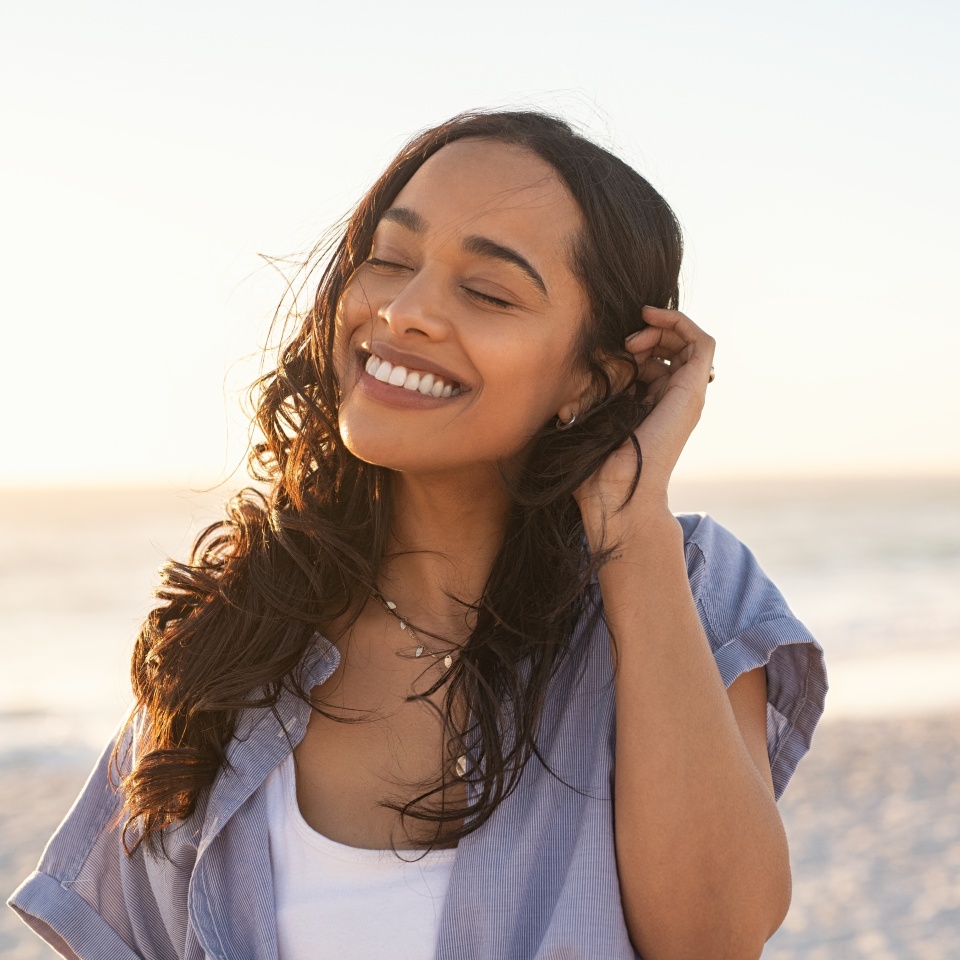 Smiling woman relaxing outdoors with eyes closed at sunset