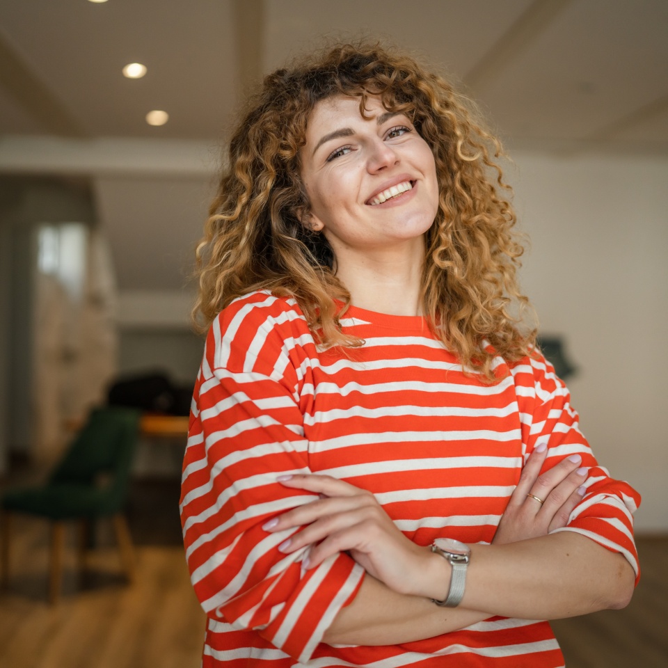 Smiling woman with curly hair standing in a cafe