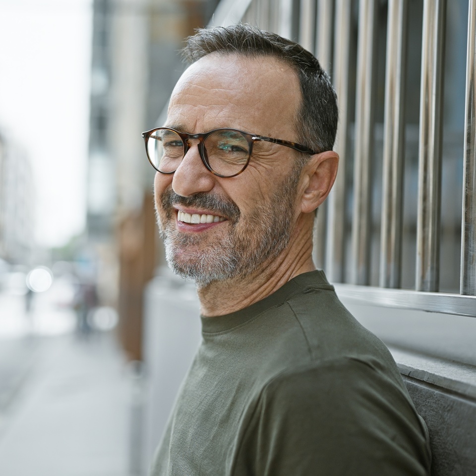 Smiling middle-aged man with grey hair standing on a city street