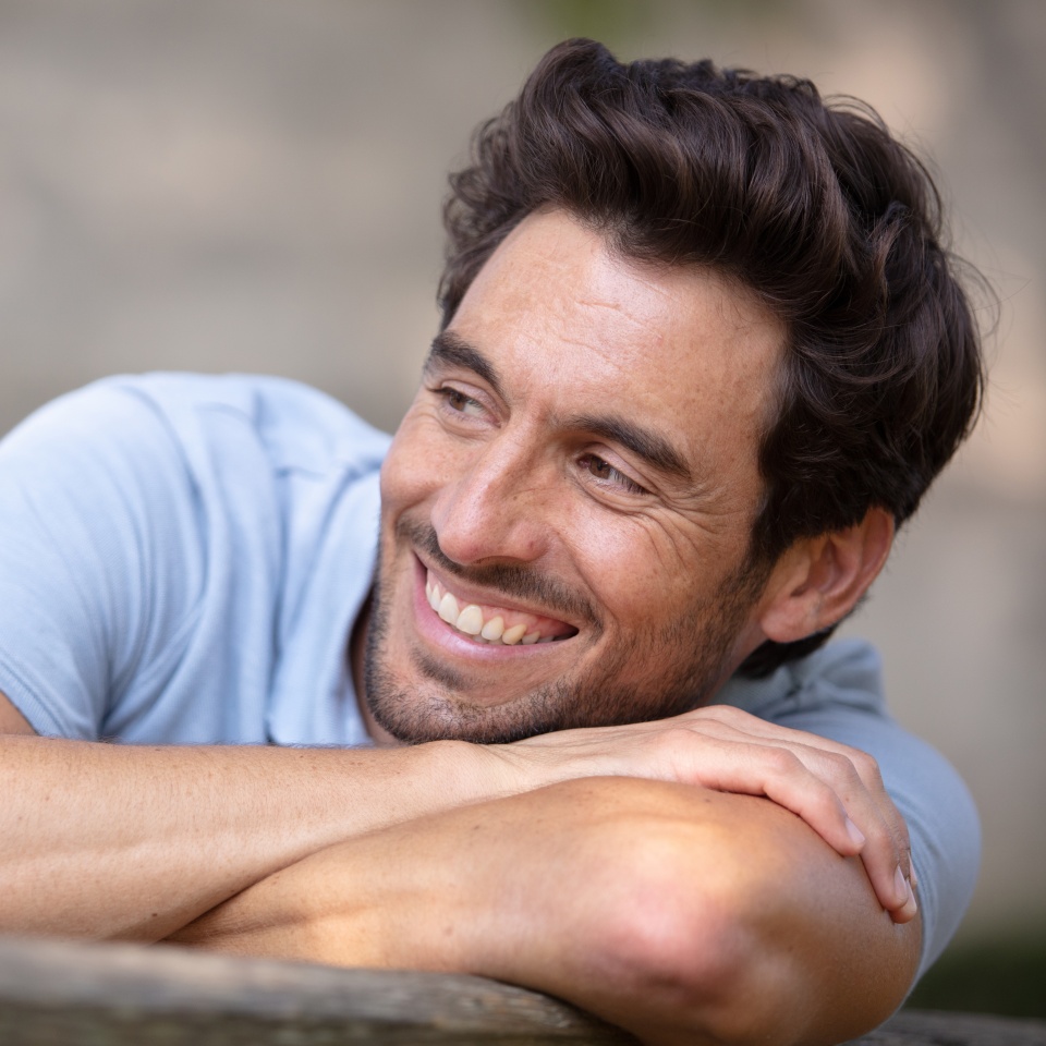 Young man relaxing on a park bench on a sunny day