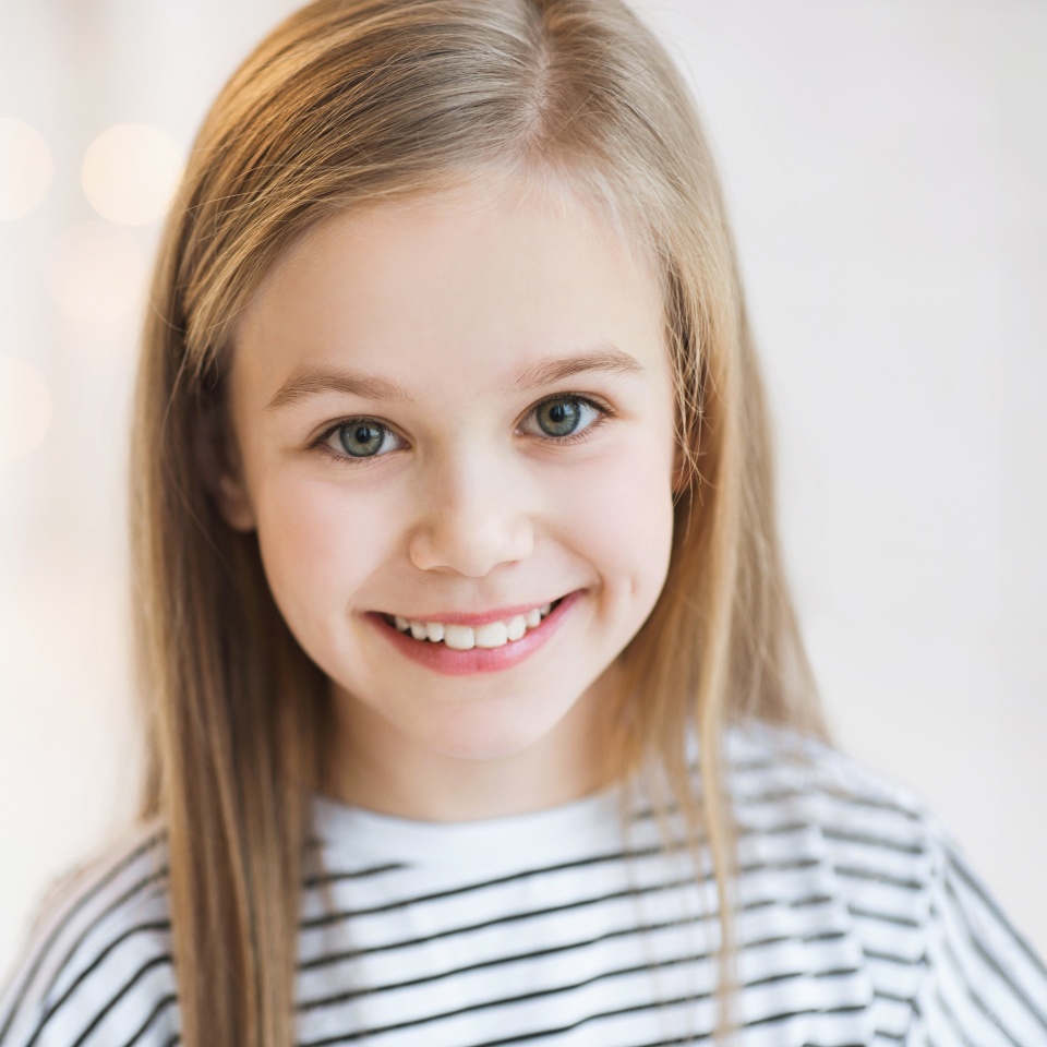Cute little girl smiling and looking at the camera at home