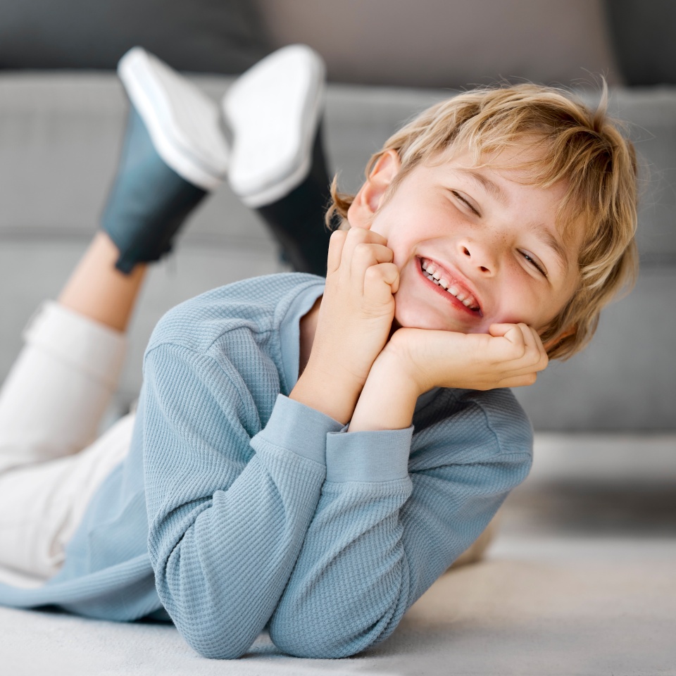 Happy young boy relaxing on the floor at home, smiling broadly