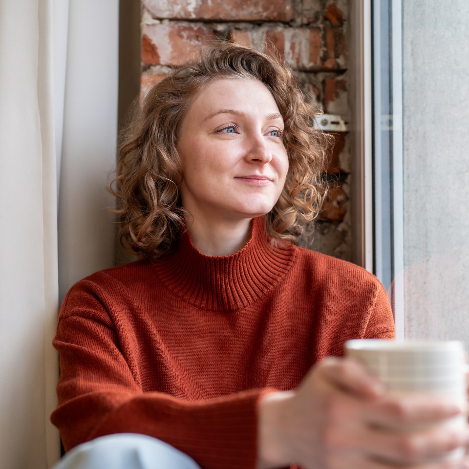 Relaxed woman smiling while holding a coffee mug