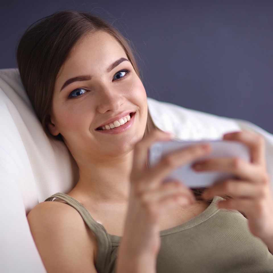 Woman lying on a couch at home using her phone
