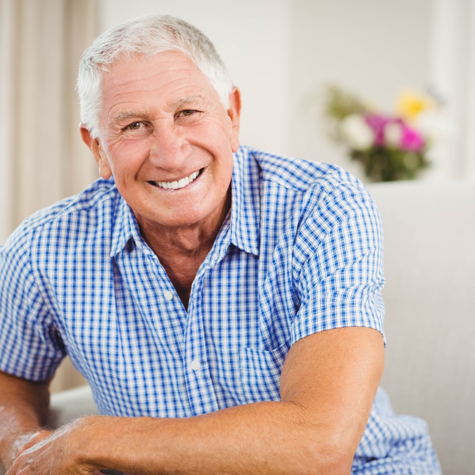 Senior man smiling at the camera in his living room