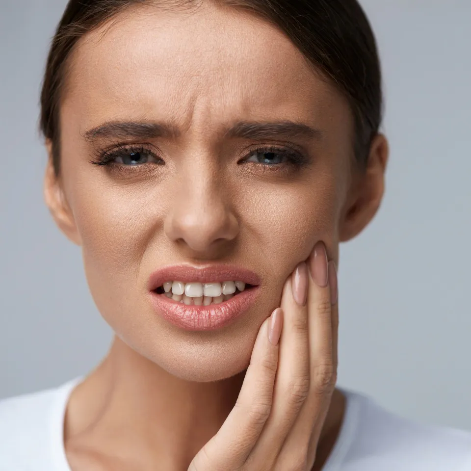 Close-up of a young woman wincing in pain from a toothache