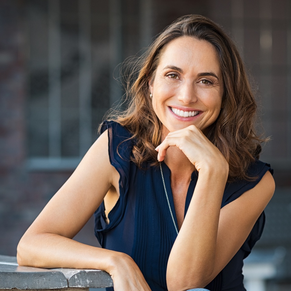 Smiling mature woman sitting on a bench at an outdoor cafe