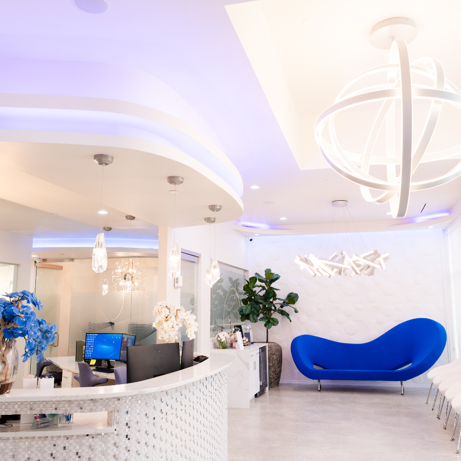 Bright Millennium Smiles office lobby with curved reception desk, blue couch, and plants