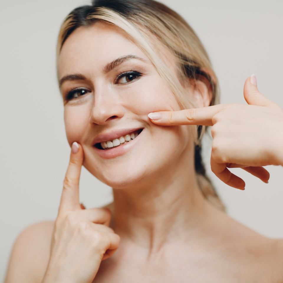 Young woman smiling while doing a facial self-massage