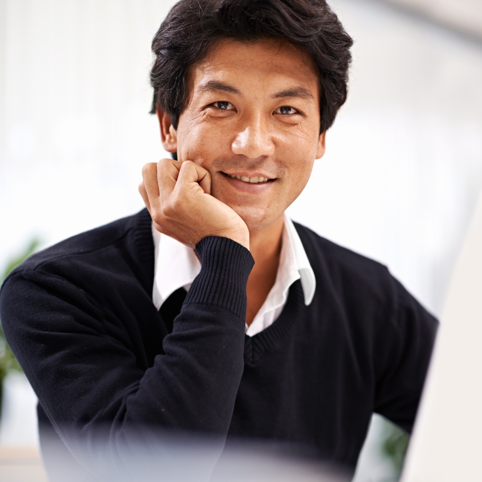 Smiling businessman working on a laptop at his desk