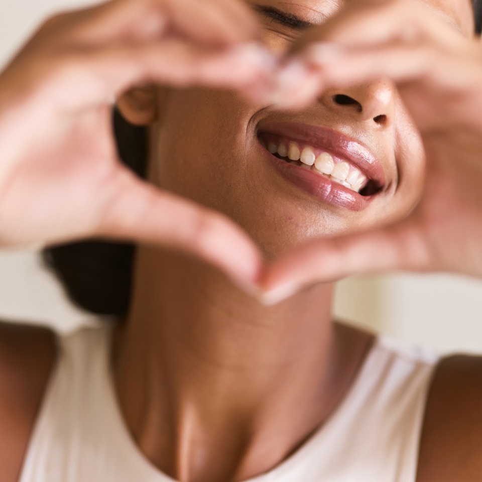Dental Care Smile. Woman Making a Heart Shape with Her Hands, Emphasizing Happiness, Positivity, and Oral Health. Perfect for Wellness and Lifestyle Themes.